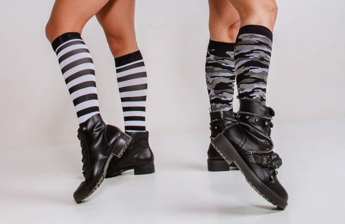 Foto de duas pessoas, com foco nas pernas, vestindo meias compressivas e botas